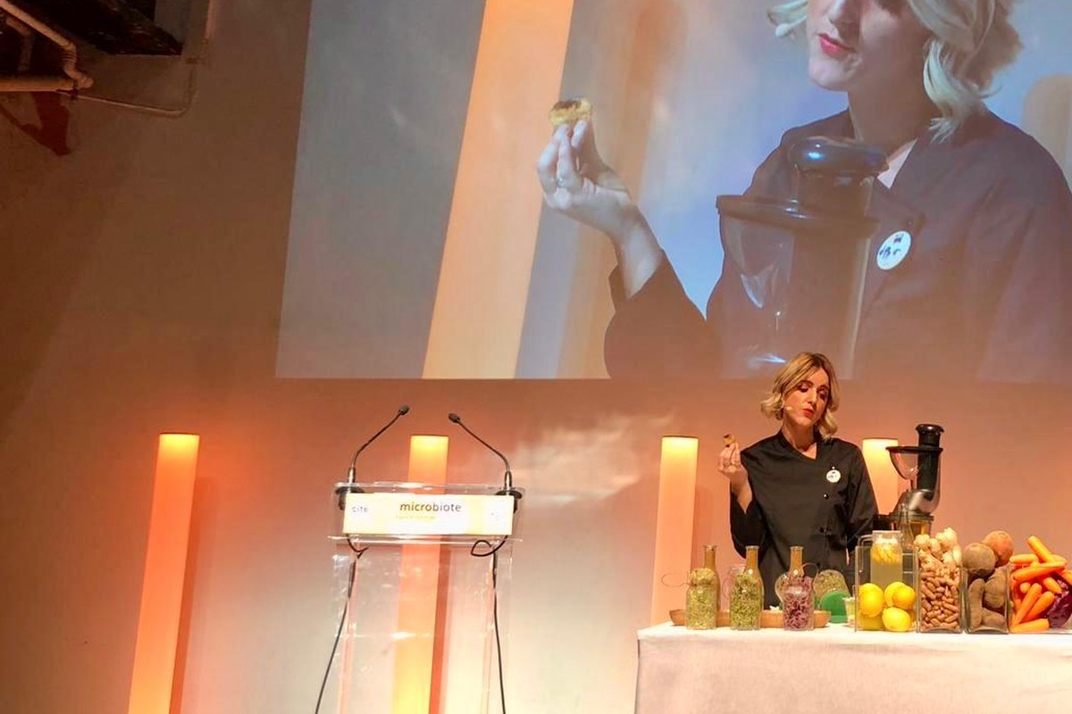 Bénédicte Coutheillas en démonstration culinaire sur scène, devant un écran de projection.